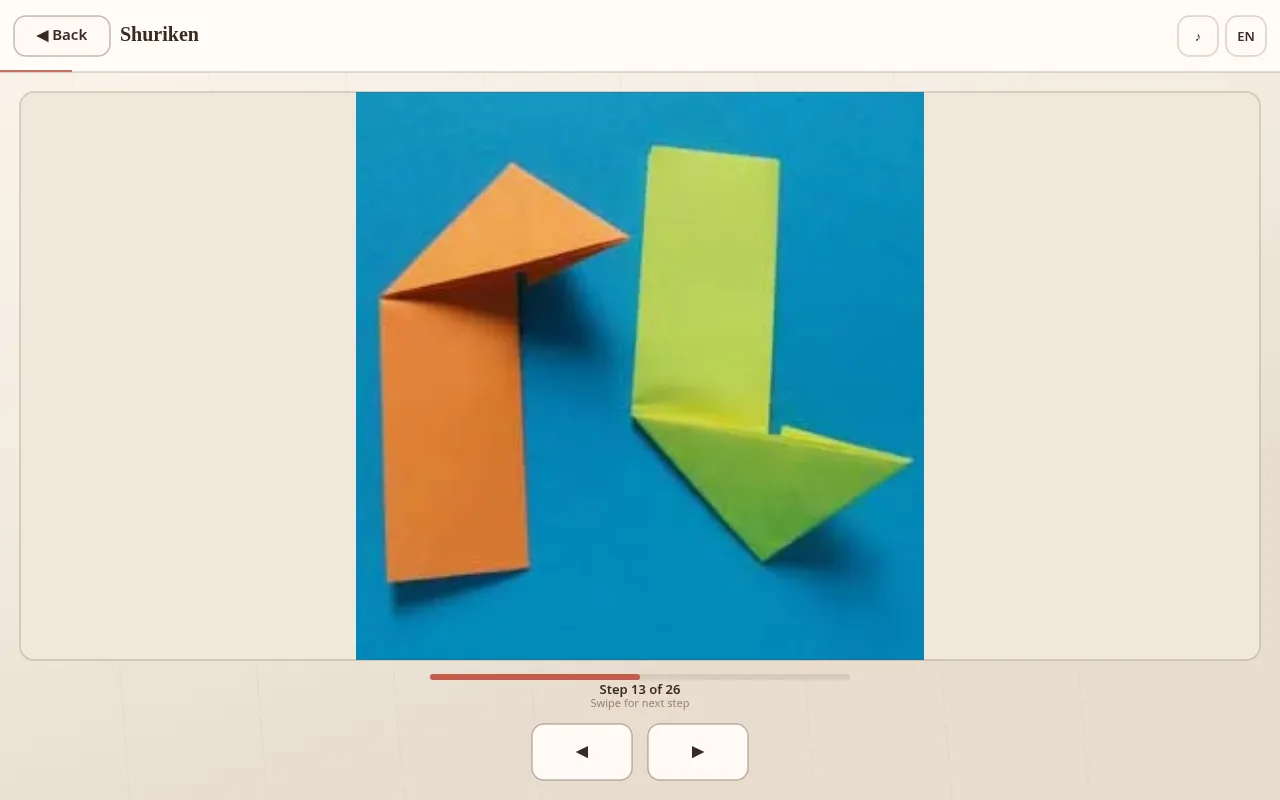 Shuriken Step 13 of 26: orange and green paper modules with mirrored triangular folds on a blue background, progress bar about halfway
